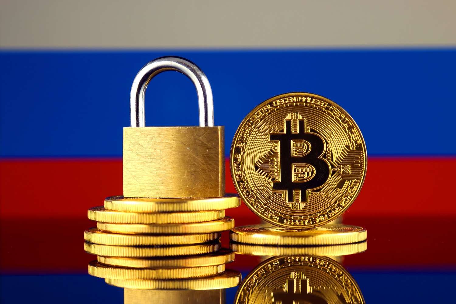 Кучи монет, символизирующих Биткоин, и замок на фоне российского флага
